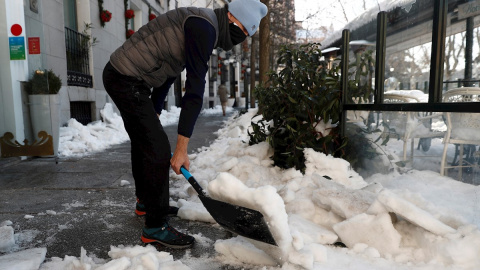 Un hombre retira nieve de la acera este lunes en Madrid.