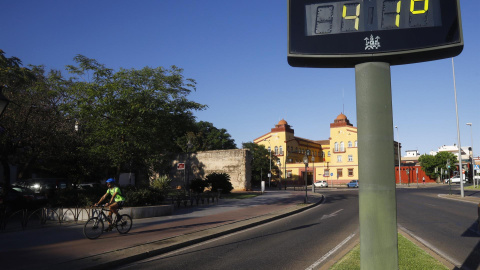 Un ciclista pasa junto a un termómetro que marca 41 grados a última hora de la tarde este jueves, en una jornada marcada por el intenso calor en Córdoba.