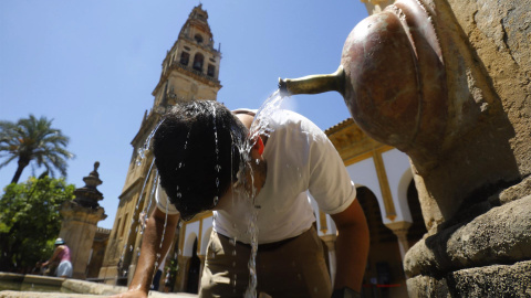 un turista se refresca en una de las fuentes del Patio de los Naranjos de la Mezquita catedral de Córdoba para aliviar las altas temperaturas.