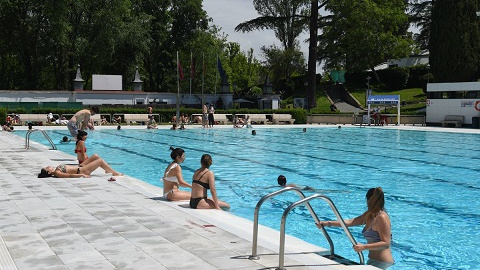 Varias personas se bañan y toman el sol, en la piscina municipal de Casa de Campo, a 14 de mayo de 2022, en Madrid (España).