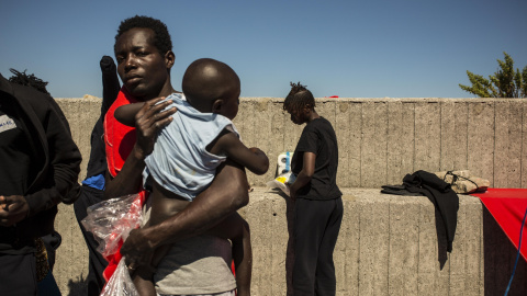 Una mujer subsahariana sostiene a su hijo antes de ser trasladados a otra parte del puerto de Algeciras. Cerca e 400 migrantes han pasado varias días enteros en los barcos de rescate o en el suelo por falta de espacio en otros lugares. JAIRO VARGAS