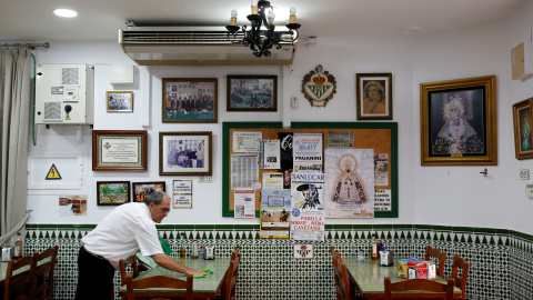 Un camareno limpia una mesa en el restaurante donde trabaja, en Chipiona (Cádiz). REUTERS / Marcelo del Pozo