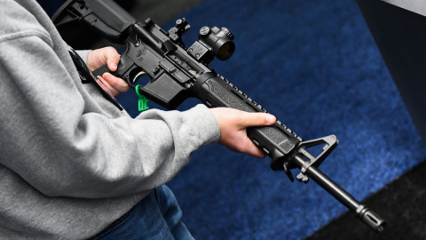 Un joven sostiene un rifle exhibido durante la reunión anual de la Asociación Nacional del Rifle (NRA) en el Centro de Convenciones George R. Brown, en Houston, Texas, el 28 de mayo de 2022.