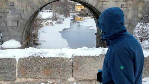 Un hombre observa el río Adaja, prácticamente congelado, a su paso por Ávila.