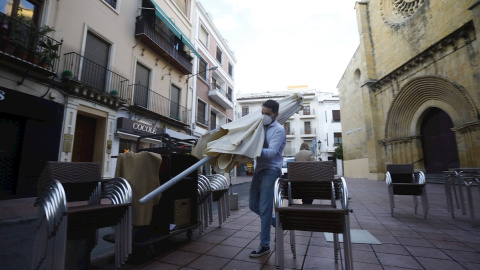 Un trabajador recoge el mobiliario de la terraza de un restaurante en el centro de Córdoba.