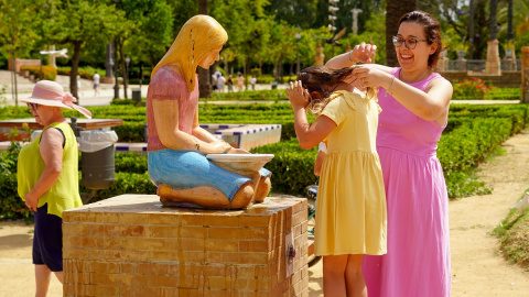 Una madre refresca a su hija en una fuente de el Parque de Maria Luisa en la primera ola de calor con temperaturas que sobrepasaran los 40 grados a 12 de junio del 2022 en Sevilla (Andalucía, España)