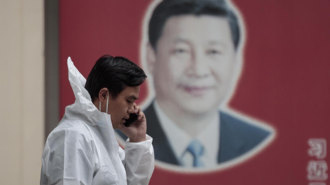 Un hombre con equipo de protección habla por teléfono en la calle, frente al cartel del presidente chino Xi Jinping, en medio del bloqueo de Covid-19 en Shanghái, China, el 23 de mayo de 2022.