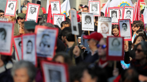 Activistas por los derechos humanos con pancartas con imágenes sobre los desaparecidos durante la dictadura de Pinochet - Reuters