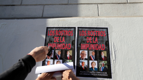 Chilenos pegan carteles en la pared con imágenes de los políticos del país que hacen llamar "los rostros de la impunidad" - Reuters