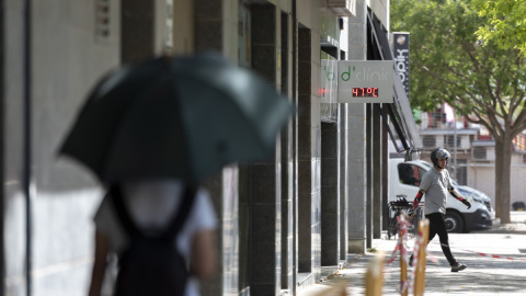 15/06/2022 Una joven camina por una calle bajo un termómetro que indica los 47ºC este miércoles, tercer día de ola de calor en Cataluña, que, según las previsiones, aún será más sofocante mañana, para alcanzar su máximo el viernes, a 15 de juni