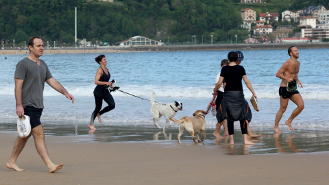 Varias persona caminan y corren con perros en la playa de La Concha en mayo de 2020 (Archivo).