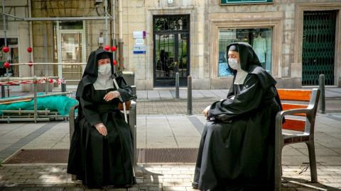 Dos monjas descansan en bancos manteniendo la distancia de seguridadhoy en el centro de Santander.