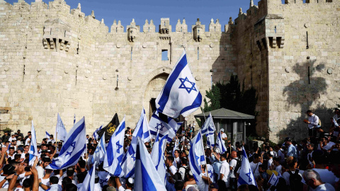 Los israelíes bailan y cantan mientras sostienen banderas nacionales israelíes junto a la puerta de Damasco en la ciudad vieja de Jerusalén.