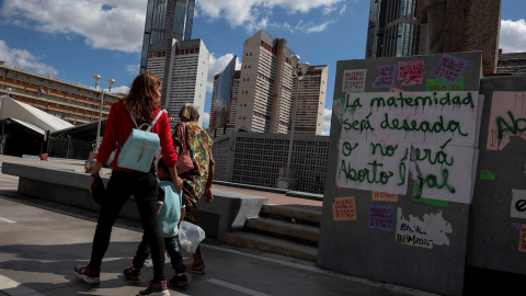 Varias personas caminan frente a un grafiti que dice "La maternidad será deseada o no será aborto legal" en una pared, el 16 de enero de 2021, en Caracas (Venezuela). Una niña de 13 años que era abusada sexualmente por un vecino interrumpió, de maner