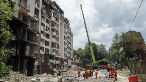 Los trabajadores comunales limpian los escombros frente a un edificio residencial dañado luego de los ataques aéreos rusos en el distrito Shevchenkivskiy de Kyiv (Kiev), Ucrania, el 26 de junio de 2022.