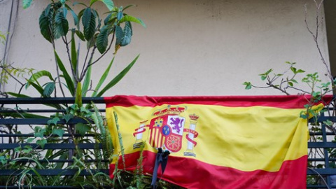 Banderas de España con crespones negros en un balcón.