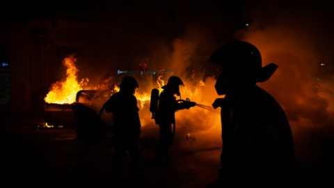 Els Bombers apaguen un foc generat en el transcurs dels aldarulls després de la manfestació per l'empresonament del raper Pablo Hasel a Barcelona.