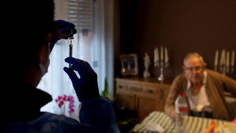 Una enfermera administra la primera dosis de la vacuna BioNTech Pfizer a un paciente mayor de 80 años en su domicilio del barrio del Raval de Barcelona.