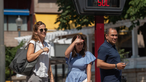 Varias personas pasan ante un termómetro al sol que marca 50 grados, hoy martes en Ourense, que supera las previsiones y llega a los 43,5 grados