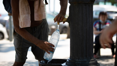 Un hombre rellena una botella de agua en una fuente en el parque de la Barceloneta, a 13 de julio de 2022, en Barcelona, Catalunya (España).