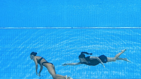 Un miembro del Equipo de EE. UU. (R) nada para recuperar a Anita Alvarez (L) de EE. UU., Del fondo de la piscina durante un incidente en las finales de natación artística libre en solitario de mujeres, durante el Campeonato Mundial Acuático de Budapest