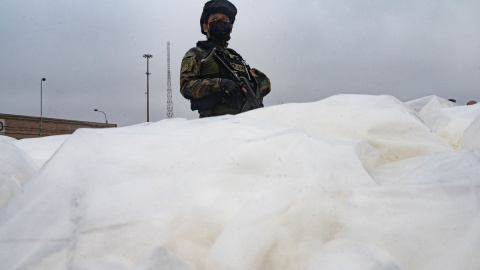 Un policía antidrogas hace guardia junto a la cocaína incautada en una instalación aduanera en el puerto de Callao, Perú, el 11 de junio de 2022.