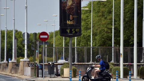 18/07/2022 - Una persona pasa en bicicleta por delante de un termómetro que marca 45º durante la ola de calor en Sevilla, el 10 de julio de 2021.