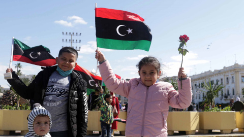 Niños libios sosteniendo banderas libias un día antes de las conmemoraciones del décimo aniversario del levantamiento contra el exlíder Moamer Kadhafi, en Trípoli, Libia, el 16 de febrero de 2021.