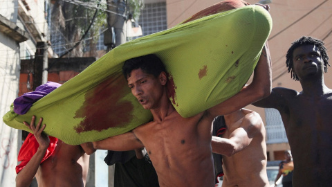 Personas cargan un cadáver durante una operación policial contra bandas de narcotraficantes en el complejo de favelas de Alemao, en Río de Janeiro