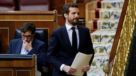 El líder del PP, Pablo Casado, se dirige a la tribuna del Congreso y pasa por el lado del exministro de Sanidad, Salvador Illa.