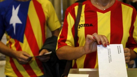 Una ciudadana deposita su voto en una mesa de en un colegio electoral de Barcelona durante el referéndum que tuvo lugar el 9-N del año 2014.- EFE