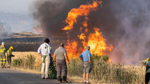 Varios vecinos observan las llamas del incendio declarado este domingo por la tarde en el término municipal de Quintanilla del Coco, en Burgos.