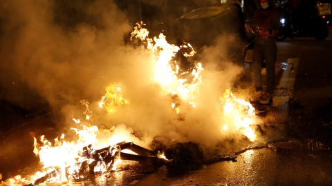 Restos de contenedores ardiendo en el centro de Barcelona este sábado, durante las protestas por el encarcelamiento del rapero Pablo Hasél.