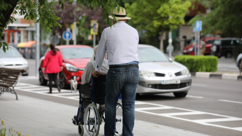 Un hombre pasea a una persona de edad avanzada en silla de ruedas. Imagen de Archivo.