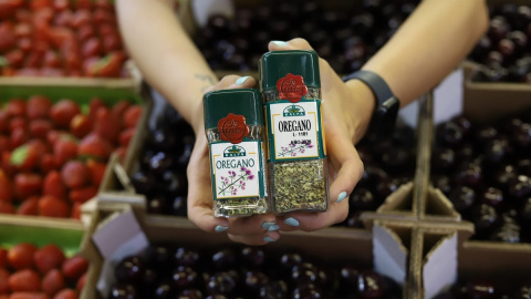 Ana, una frutera del mercado municipal de Puerta del Ángel, Madrid, muestra dos botes de orégano. El pequeño cuesta lo mismo que el grande hace un año.