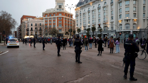 Efectivos policiales vigilan a asistentes a una sentada improvisada en la plaza de Neptuno de Madrid.