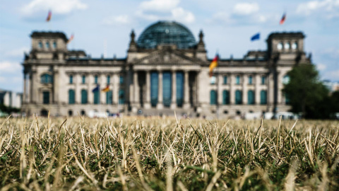 La hierba frente al edificio del Reichstag, la sede del Bundestag del Parlamento alemán, se seca durante las altas temperaturas, en el parque Lustgarten en Berlín, Alemania, el 04 de agosto de 2022. El Servicio Meteorológico Alemán (DWD) espera que la