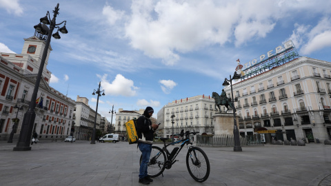 Un repartidor de la empresa Glovo mira su teléfono en la Puerta del Sol.