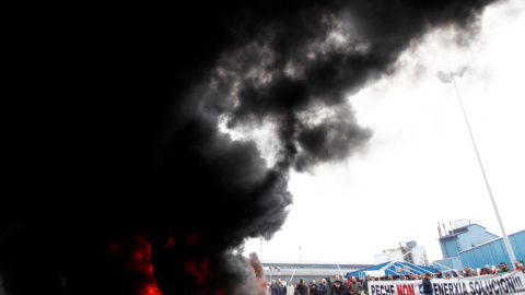 Trabajadores de la planta Alcoa de A Coruña, durante la concentración que llevan a cabo a las puertas de la fábrica, donde han quemado neumáticos y cortado el tráfico, en protesta y en lucha contra el cierre de la aluminera, que supondría el despido