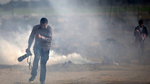 Un fotógrafo palestino trata de evitar el gas lacrimógeno lanzado por las fuerzas israelís. MOHAMMED ABED/AFP/Archivo