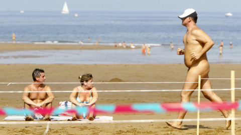 (9/09/06) Una pareja toma el sol mientras un hombre participa en la carrera nudista "Patxi Ros" de Sopelana (Euskadi), a 9 de septiembre de 2006.