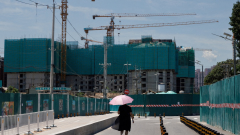 Una mujer pasa junto a varios edificios de apartamentos en construcción en Pekín. REUTERS/Thomas Peter