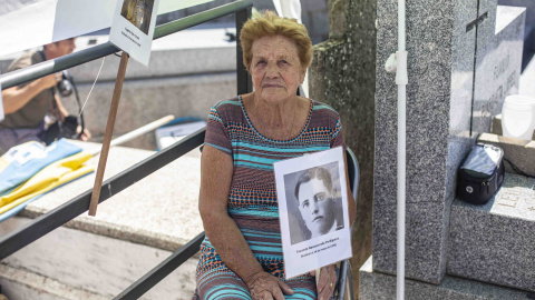 Benita Navacerrada sostiene un cartel con la foto de su padre junto a la fosa común del cementerio parroquial de Colmenar Viejo (Madrid), donde fue enterrado con decenas de republicanos fusilados en 1939.