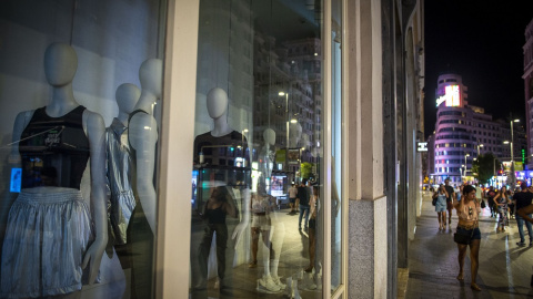 29/08/2022. Varias personas pasan por una tienda de ropa con las luces apagadas, a 10 de agosto de 2022, en Madrid