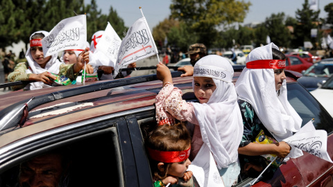 31/08/2022 Niñas afganas sostienen banderas del Emirato Islámico mientras participan en el primer aniversario de la retirada de las tropas estadounidenses de Afganistán, en una calle de Kabul, Afganistán, el 31 de agosto de 2022.