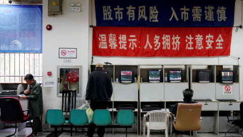 Los inversores miran los monitores que muestran información sobre acciones en una firma de brokers en Shanghai (China). REUTERS / Aly Song