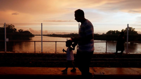 Migrantes hondureños esperan en el puente de la frontera entre Guatemala y México este domingo 21 de octubre de 2018, en Tecún Umán (Guatemala). Las personas, entre ellas niños, siguen esperando para poder ingresar en territorio mexicano y así conti