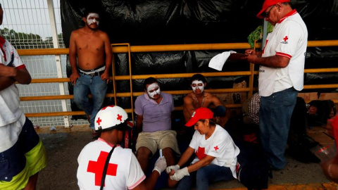 Colaboradores de la Cruz Roja asisten a migrantes hondureños, mientras esperan en el puente de la frontera entre Guatemala y México en Tecún Umán (Guatemala)