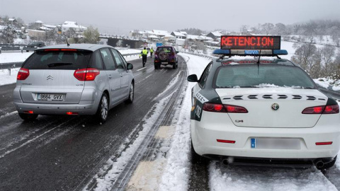 Efectivos de la Guardia Civil trabajan para descongestionar una retención por nieve en la autovía A-52, en Ourense. Las nevadas y las bajas temperaturas registradas en las últimas horas han provocado complicaciones desde primera hora de este sábado en