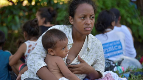 Una madre con su hijo en brazos tras haber logrado instalarse en Ciudad Cuauhtémoc. EFE/Rodrigo Pardo